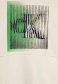 Krémová mikina s geometrickou grafikou v zelených a šedých tónech, s texturovanými detaily a kontrastními černými akcenty.