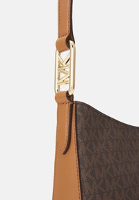 Bolso de cuero marrón con un patrón, una correa beige y herrajes metálicos dorados. Los detalles notables incluyen un diseño de hebilla geométrica.