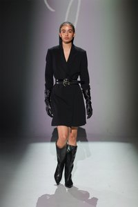 Črno strukturirano blazer obleko z dvema pasom, v kombinaciji z dolgimi črnimi usnjenimi rokavicami in črnimi usnjenimi škornji do kolen.