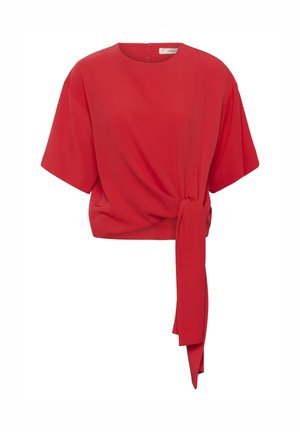 Rode blouse met korte mouwen, een ronde hals en een asymmetrisch knoopdetail aan de voorkant dat aan de rechterkant hangt.