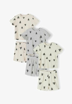 Trois ensembles de hauts à manches courtes et de shorts en crème et gris, chacun décoré de motifs de cœurs noirs dispersés.