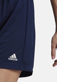 Tumedad sinised sportlikud lühikesed püksid sileda tekstuuriga, mille vasakus allnurgas on valge Adidas'i logo.
