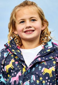Farverig vandtæt jakke med en navy bund og pink og gule enhorn, blomster og stjerner. Indeholder lynlås og hætte.