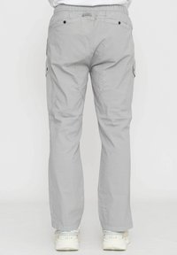 Pantaloni cargo grigi chiari con vita elasticizzata, dotati di tasche laterali e taglio dritto. Indossati con scarpe da ginnastica chiare.