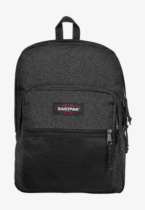 Mochila negra con un acabado texturizado, que cuenta con un bolsillo delantero con cremallera, parche con el logo y correas ajustables. Detalles de malla en la parte frontal.