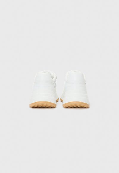 Scarpe sportive bianche con superficie texturizzata, suola in gomma e altezza media, caratterizzate da un design minimalista e una palette di colori neutri.