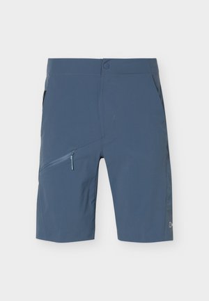 Plave kratke hlače do koljena s prednjim džepom na patentni zatvarač, kopčanjem na dugme i bočnim džepovima na jednobojnoj pozadini.