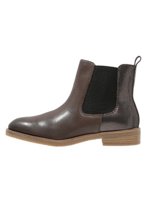 Bottine en cuir marron avec des panneaux latéraux en élastique, un accent côtelé et un dos texturé contrastant. Semelle en bois plate.