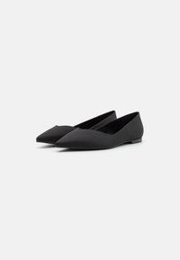 Czarne płaskie buty z punktowanym noskiem, wykonane z gładkiej tkaniny. Cechują się niskim obcasem i smukłą sylwetką, co nadaje im minimalistyczny wygląd.