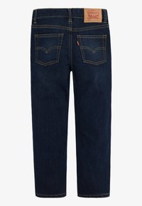 Tumši zili džinsa džinsi ar taisnu piegriezumu, dzeltenām šuvēm, divām aizmugures kabatām un firmas ādas uzliku pie vidukļa.