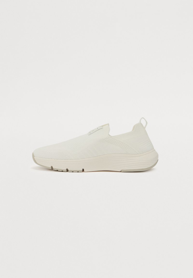 Hvite slip-on joggesko med teksturert overdel, elastisk krage og polstret såle. Minimalistisk design uten synlige snørebånd.