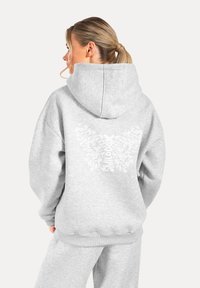 Hellgrauer Hoodie mit großem weißem Schmetterlingsgrafik und Text auf dem Rücken, gefertigt aus weichem Stoff mit gerippten Bündchen und Saum.