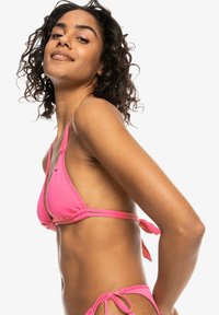 Set di bikini rosa con top triangolare, spalline regolabili e lacci, texture liscia e accenti di colore a contrasto al centro.