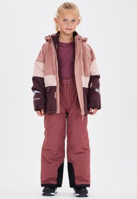Veste de ski rose et bordeaux avec un design bicolore, associée à un pantalon de neige rose assorti. Comprend une capuche et des poches zippées.