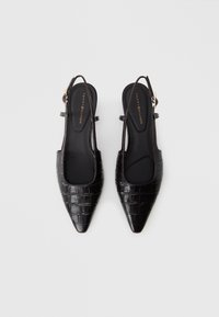 Čierne slingback topánky s špicatou špičkou, textúrou sembossovaného kroko, štíhlymi remienkami a zlatými doplnkami. Hladké vnútorné podšívka a plochá podrážka.