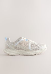 Vīriešu sporta apavu kurpes gaiši bēšā krāsā. Tām ir elpojošs tīkls uz augšdaļas, baltas detaļas, teksturēts sānu panelis un gaiši zils mēles cilpiņa.