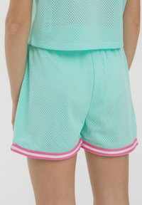 Shorts in maglia verde menta con un design leggero, vita elastica e bordo a strisce rosa lungo l'orlo. Adatti per l'abbigliamento sportivo.