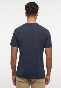 Námořnická modrá bavlněná tričko s krátkými rukávy, kulatým výstřihem a rovný střih. Hladká textura, minimální detaily, jednoduchý vzor.