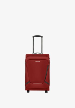 Valise souple rouge avec une poignée rétractable, deux roues et des compartiments zippés. Présente une texture de tissu lisse et un détail de logo.