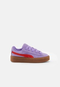 Fialová semišová teniska s červeným pruhem, strukturovanou tanovou gumovou podrážkou, kulatou špičkou a barevně sladěnými tkaničkami, s logem Puma na straně.