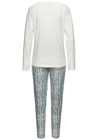 Haut à manches longues blanc avec un col rond, associé à un pantalon imprimé à rayures verticales vertes et blanches. Tissu doux, coupe décontractée.
