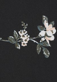 Tessuto nero con un motivo floreale, caratterizzato da fiori rosa pallido e foglie verdi, esposto su uno sfondo texturizzato.