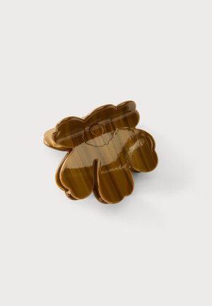 Brun plastik hårklemme formet som en blomst med fem afrundede kronblade, placeret på en ensfarvet hvid baggrund.