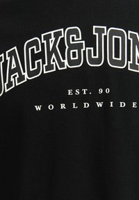 Čierne tričko s veľkým bielym textom "JACK & JONES" a menším textom "EST. 90 WORLDWIDE" v jednoduchom, klasickom písmovom štýle.