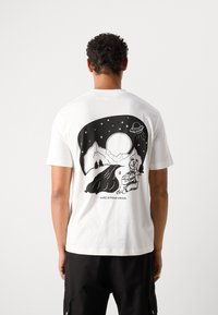 Witte katoenen t-shirt met een zwart grafisch ontwerp van bergen, een beer en een UFO tegen een sterrenhemel, gelabeld "MARC O'POLO DENIM."