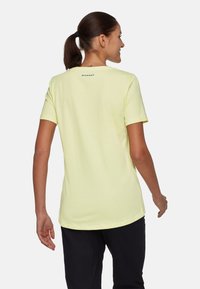 Lichtgele t-shirt met korte mouwen en ronde hals, voorzien van een zwart logo op de achterkant, gemaakt van zachte katoen.