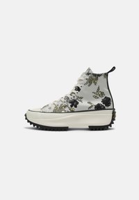 Sneakers za kostkę z błyszczącą srebrną tekstylną cholewką, czarnym i złotym kwiatowym wzorem oraz masywną białą podeszwą platformową z zygzakowymi bieżnikami.