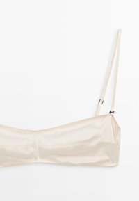 Satin bandeau-bh i lyse beige med justerbare stropper og en glat tekstur; har sømløs konstruktion for et elegant udseende.