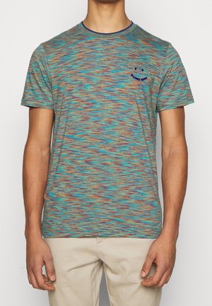 Homme portant une chemise multicolore bleu, orange et vert à manches courtes avec un petit graphique de smiley bleu foncé sur la poitrine.