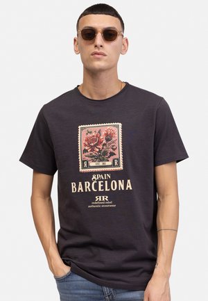 Tamno sivi majica kratkih rukava s cvjetnim otiskom i natpisom "Španija Barcelona" u krem i crvenim naglascima. Glatka tekstura.