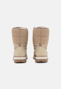 Stivali trapuntati beige con parte superiore imbottita, chiusura con lacci elastici e suola in gomma. Fodera interna morbida e parte inferiore testurizzata.