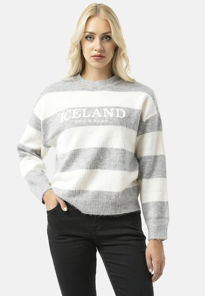 Pull rayé gris et blanc à col rond, affichant le mot "ISLANDE" en broderie blanche sur la poitrine. Texture douce.