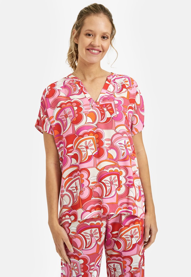 Różowa i czerwona bluzka w kwiatowy wzór z dekoltem w serek, krótkimi rękawami i luźnym krojem, wykonana z lekkiego, gładkiego materiału.