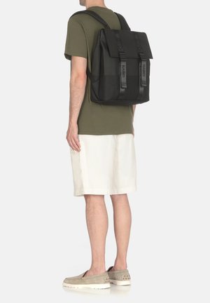 Zaino nero con un design strutturato, dotato di spallacci regolabili, chiusura a patta e accessori di marca, realizzato in materiale resistente.