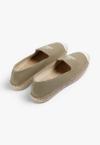 Lys oliven lærred espadriller med rund tå, elastiske sidepaneler og beige jute rebdetalje omkring sålen.