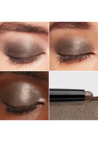 Crèmige oogschaduwstick in een donkere metallic bruine tint, met een gladde textuur. De applicator heeft een afgeronde punt voor eenvoudig gebruik.