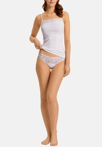 Weißes Baumwoll-Camisole mit Spitzenbesatz und Spaghettiträgern, kombiniert mit weißen Spitzenunterhosen im floralen Muster.