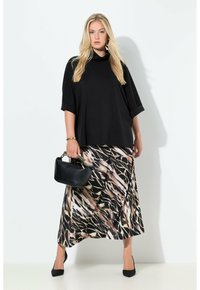 Černý top s rolákem v kombinaci s dlouhou vzorovanou sukní v neutrálních tónech. Doplňky zahrnují černou kabelku a černé podpatky. Hladká textura látky.