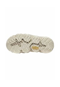 Suola di scarpa color beige chiaro con gomma testurizzata per una migliore aderenza. Presenta motivi circolari e zigzag, oltre a un logo prominente di colore giallo.