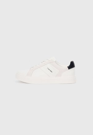 White sneakers with light pink and black accents, featuring smooth leather and suede panels, round toe, and flat rubber sole.