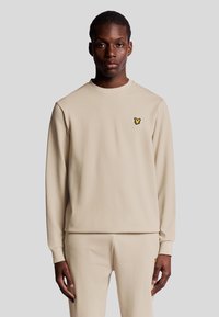 Felpa beige a maniche lunghe in un tessuto morbido, con un logo giallo sul petto. Collo rotondo semplice e orlo dritto.