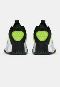 Αθλητικά παπούτσια ασπρόμαυρα με ζωηρά π�ράσινα στοιχεία, που διαθέτουν υφή στην σόλα, ενισχυμένη φτέρνα και πλέγμα στο πάνω μέρος για αναπνοή.