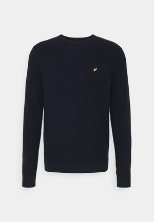 Maglione lavorato a maglia blu navy con maniche lunghe e scollo rotondo. Presenta un piccolo logo giallo sul petto. Tessuto testurizzato.
