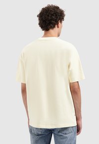 Korte mouwen, ronde hals t-shirt van lichtgele, gestructureerde stof. De achterzijde toont een losse pasvorm en subtiele stikseldetails. Casual ontwerp.