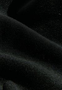 Čierny zamatový materiál s jemnou, hladkou textúrou a subtílnym leskom. Obsahuje husté, mäkké vlákna vytvárajúce bohatý, tmavý vzhľad.