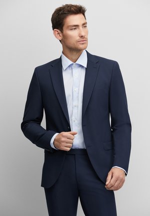 Navy suit jacket with notch lapels, paired with a light blue dress shirt featuring buttons. Smooth fabric, tailored fit, with side pockets.